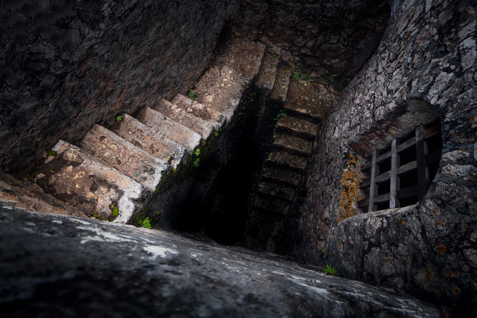 Old stone stairs spiraling down into a dark, dungeon-like passage